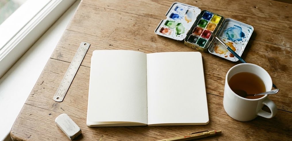 Tools for Sketching a Room Layout — Watercolor Method Watercolor notebook, pencil, and travel paint set used for hand-drawn room planning